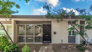 A modern two-story house with a front entrance, a small garden, and a clear sky.