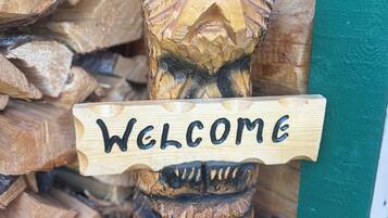 A wooden bear holding a sign that says 'WELCOME.'