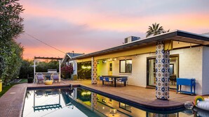 A modern house with a swimming pool, outdoor furniture, and a patio area.