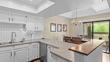 A modern kitchen with white cabinets, a large island, and a dining area with a view.