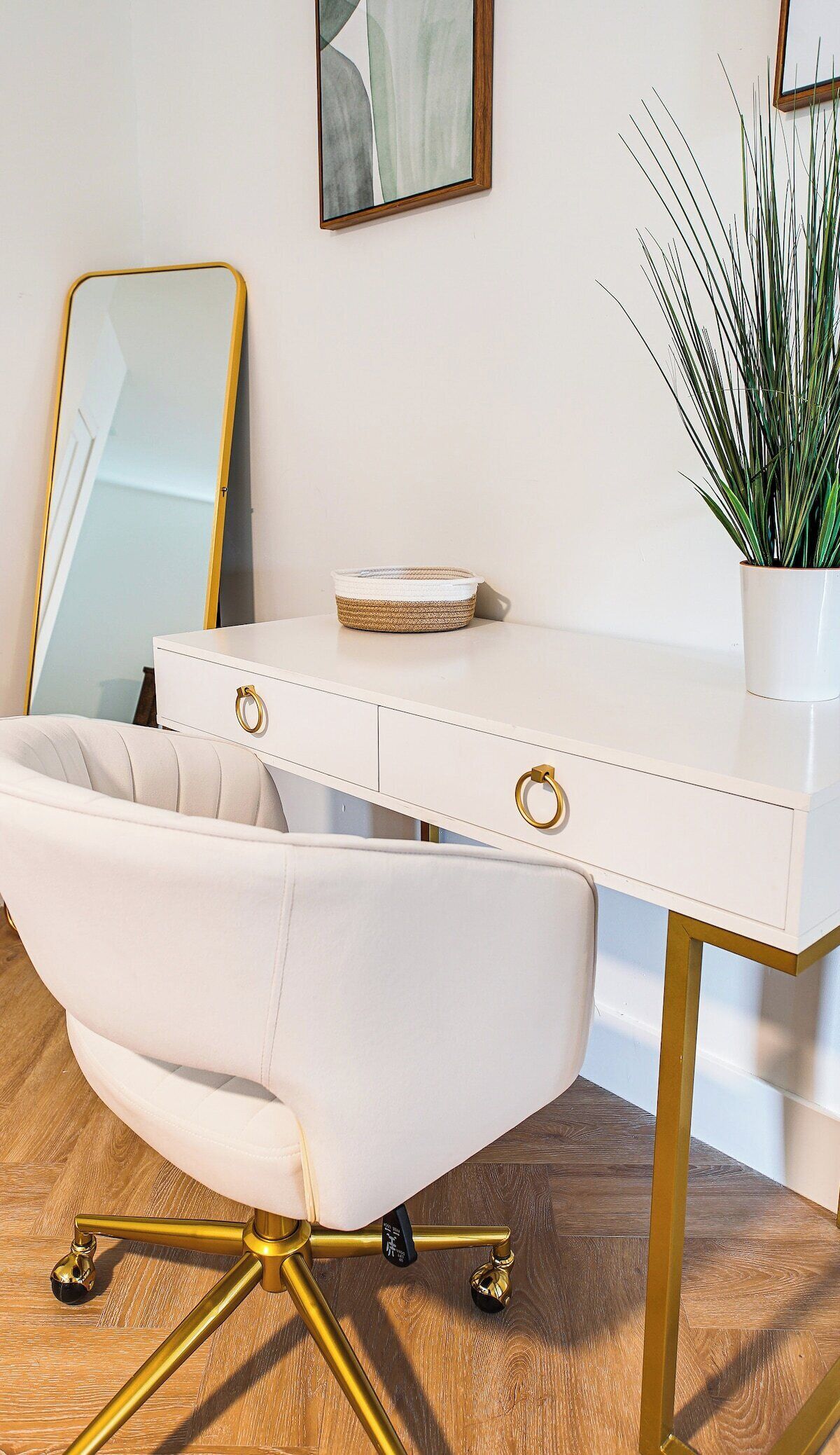 A white desk with gold accents, a white chair, and a potted plant.