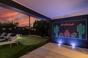 A backyard with artificial grass, lounge chairs, and a neon sign with cacti design. - Scottsdale Hangout with Private Pool and Putting Green, ideal location near Old Town (Scottsdale)