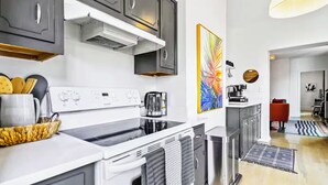 A modern kitchen with dark cabinets, a white countertop, and a stainless steel range hood. - Walk to BeltLine, Stylish 2BR w/ Deck, Sleeps 4 (Atlanta)