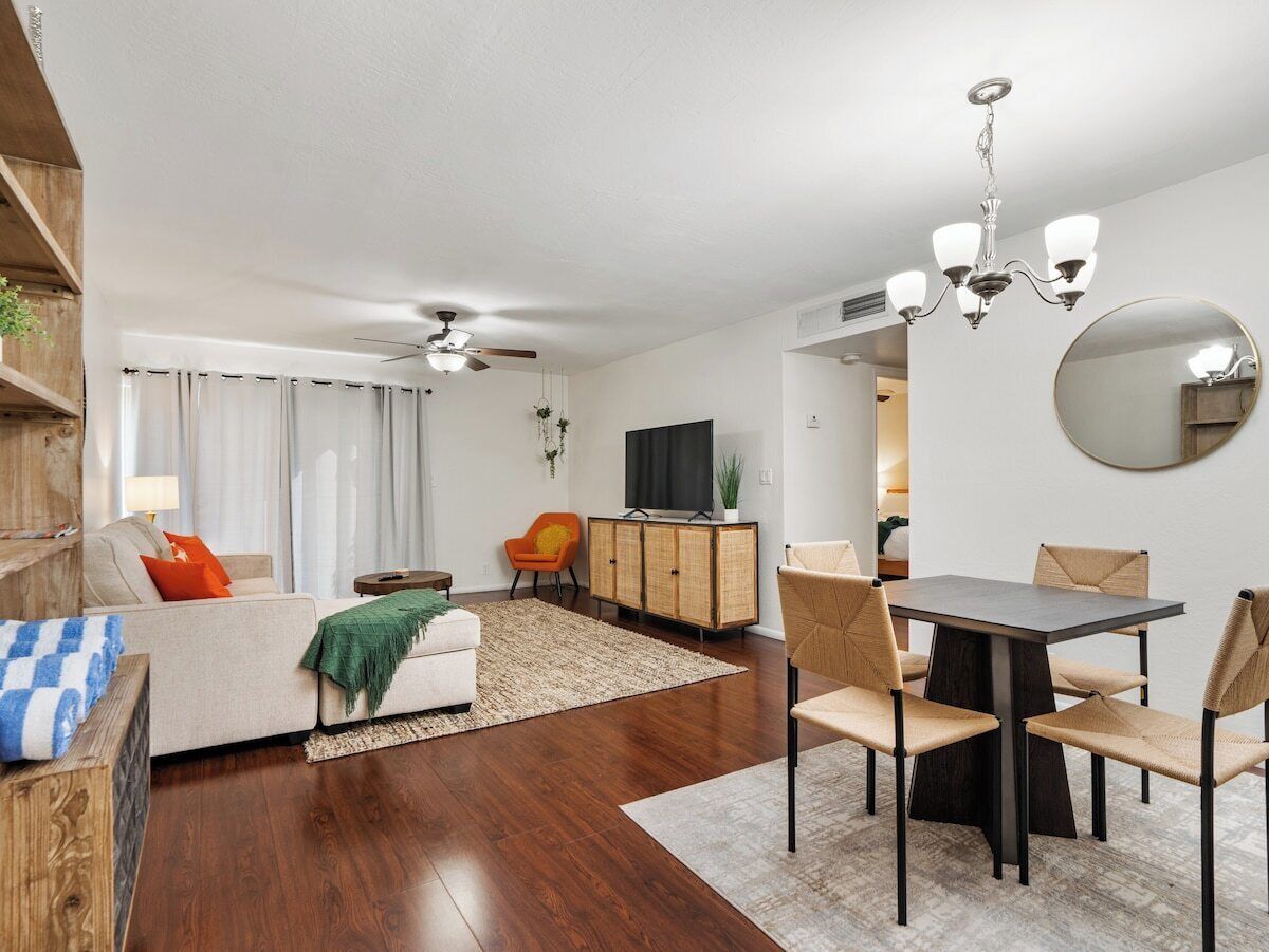 Een moderne woonkamer met een bank, eettafel en stoelen. Achterin staat een televisie en een kast.