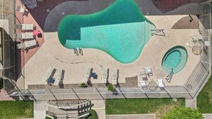 Eine Vogelperspektive auf einen Poolbereich mit mehreren Liegestühlen und einer kleinen Whirlpool.