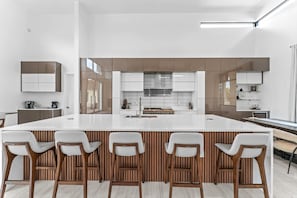 A modern kitchen with a large island, bar stools, and a built-in oven. - Luxury Modern Villa with Pool, Hot Tub, & Pickleball/Basketball Sports Court in Scottsdale (Scottsdale)