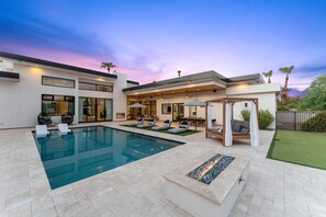 A modern house with a swimming pool, outdoor seating, and a well-maintained lawn.