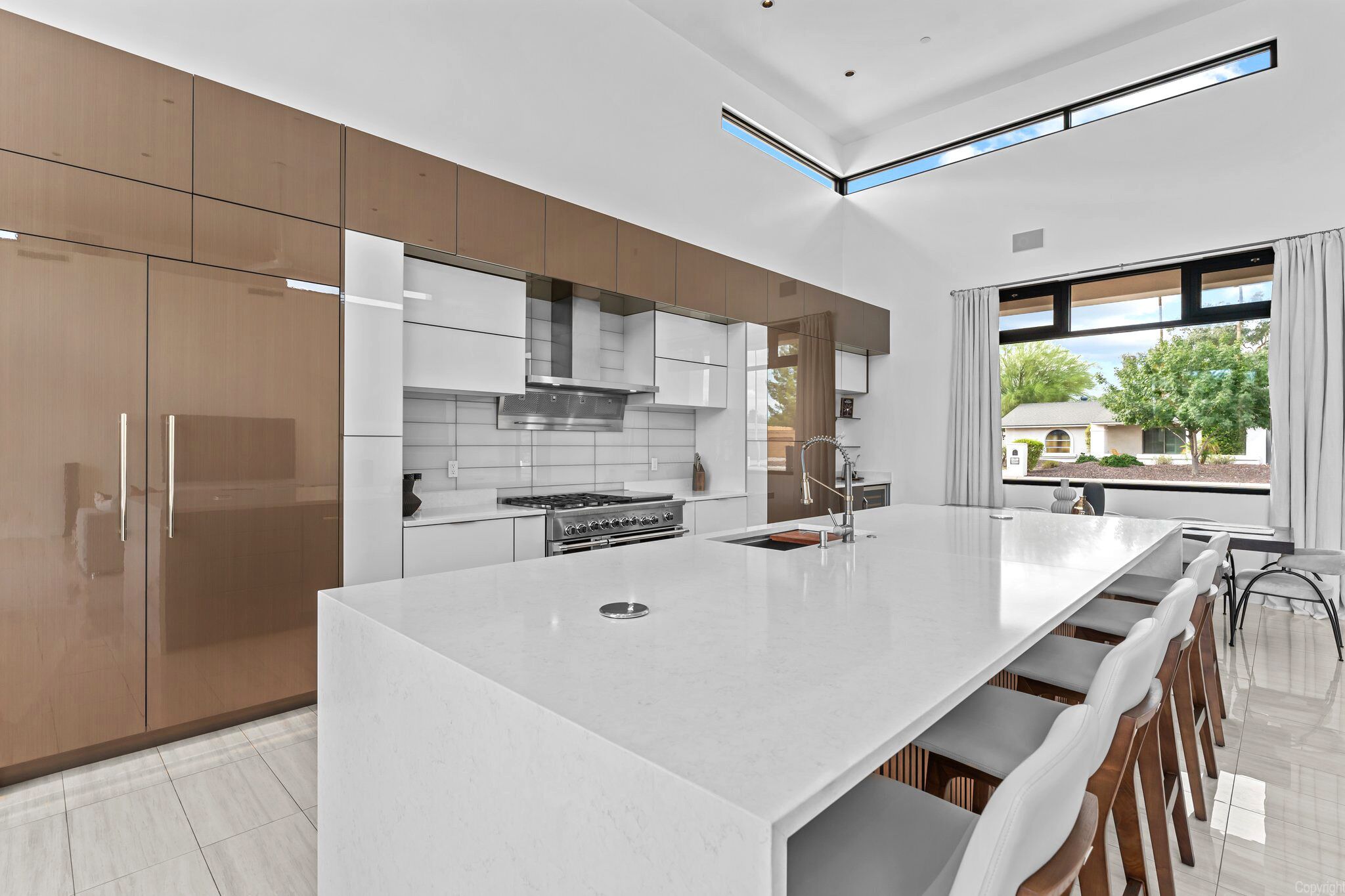 A modern kitchen with a large island, stainless steel appliances, and a view of the outdoors.
