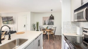 Une cuisine moderne dotée d’un îlot central, d’appareils électroménagers en acier inoxydable et d’un coin repas avec une table et des chaises.