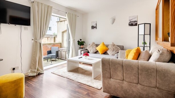 A modern living room with a sofa, coffee table, and a TV mounted on the wall. - Canary Wharf Gem - Prvt Parking - Fast WiFi - O2 & Excel - Sleeps 4 (London)