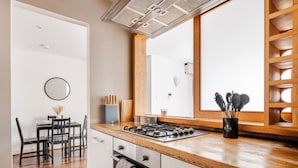 A modern kitchen with a wooden countertop, gas stove, and a dining area with a table and chairs. - Canary Wharf Gem - Prvt Parking - Fast WiFi - O2 & Excel - Sleeps 4 (London)