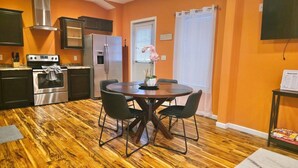 Cocina compacta con electrodomésticos modernos, una mesa de comedor con cuatro sillas y piso de madera.