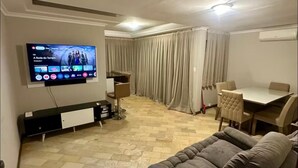 A living room with a flat-screen TV, a sofa, a dining table, and a curtain-covered window. - The most complete and in the best location in Florianópolis-SC. (florianópolis)
