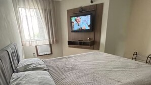 A hotel room with a large bed, a television mounted on the wall, and a window with curtains. - The most complete and in the best location in Florianópolis-SC. (florianópolis)