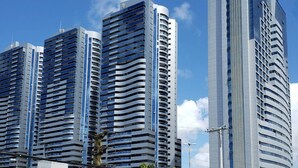 A modern high-rise building with multiple balconies and a curved design. - Dolphins Tech (Salvador)