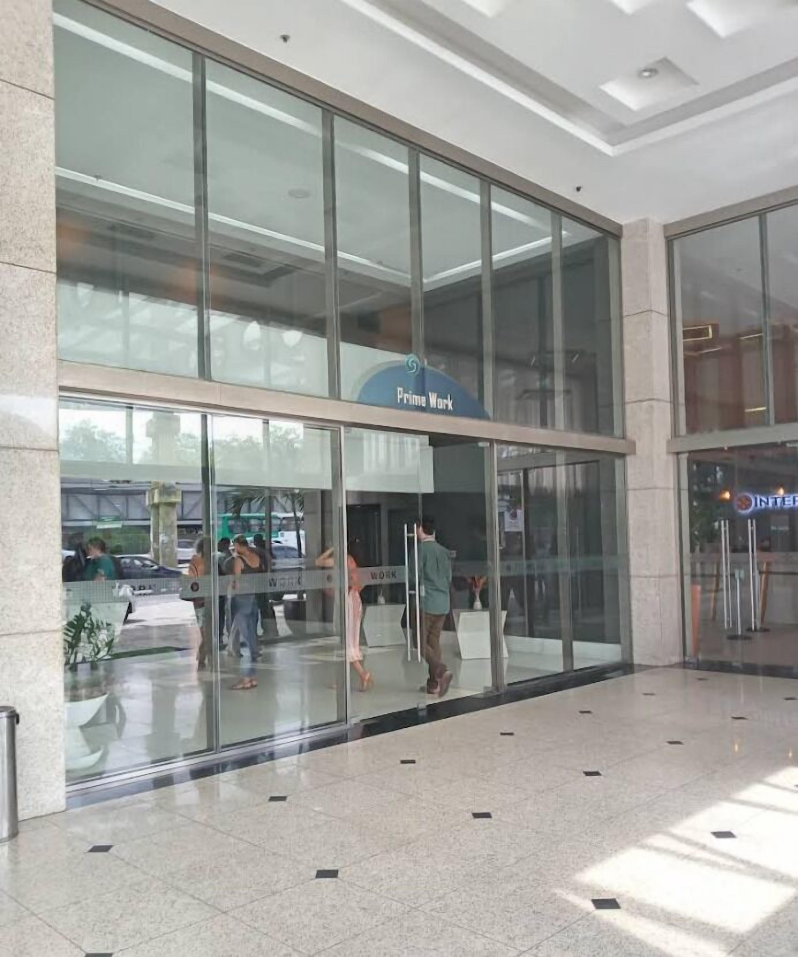 Un edificio moderno con grandes ventanales de vidrio y un letrero que dice "Prime Work".