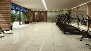 A modern gym with exercise equipment, a large mirror, and a TV screen on the wall. - Dolphins Tech (Salvador)