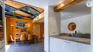 Eine moderne Küche mit einer großen Kochinsel, einem Essbereich mit Holztisch und Stühlen sowie einem Oberlicht über dem Essbereich.