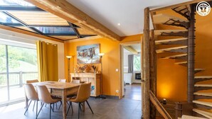 Ein Essbereich mit Holztisch und -stühlen, einem Bild an der Wand und einer Treppe mit Holzwandung.