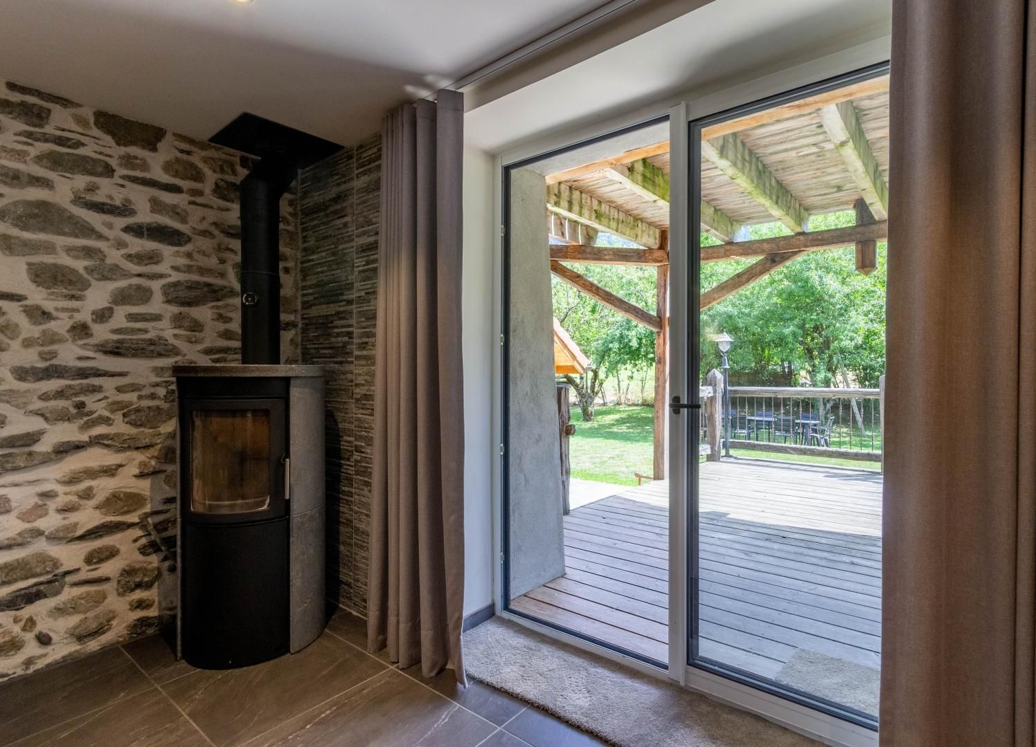 Una habitación con pared de piedra, chimenea y puerta corrediza de vidrio que da a una terraza exterior.
