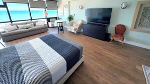 A modern living room with a large bed, a TV, and a view of the ocean. - Spectacular views - direct oceanfront studio w/kitchen & pool (Daytona Beach)