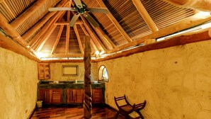 A spacious room with a high ceiling, wooden beams, a ceiling fan, and a wooden floor.