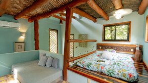 A room with a wooden bed, a sofa, and a ceiling fan.