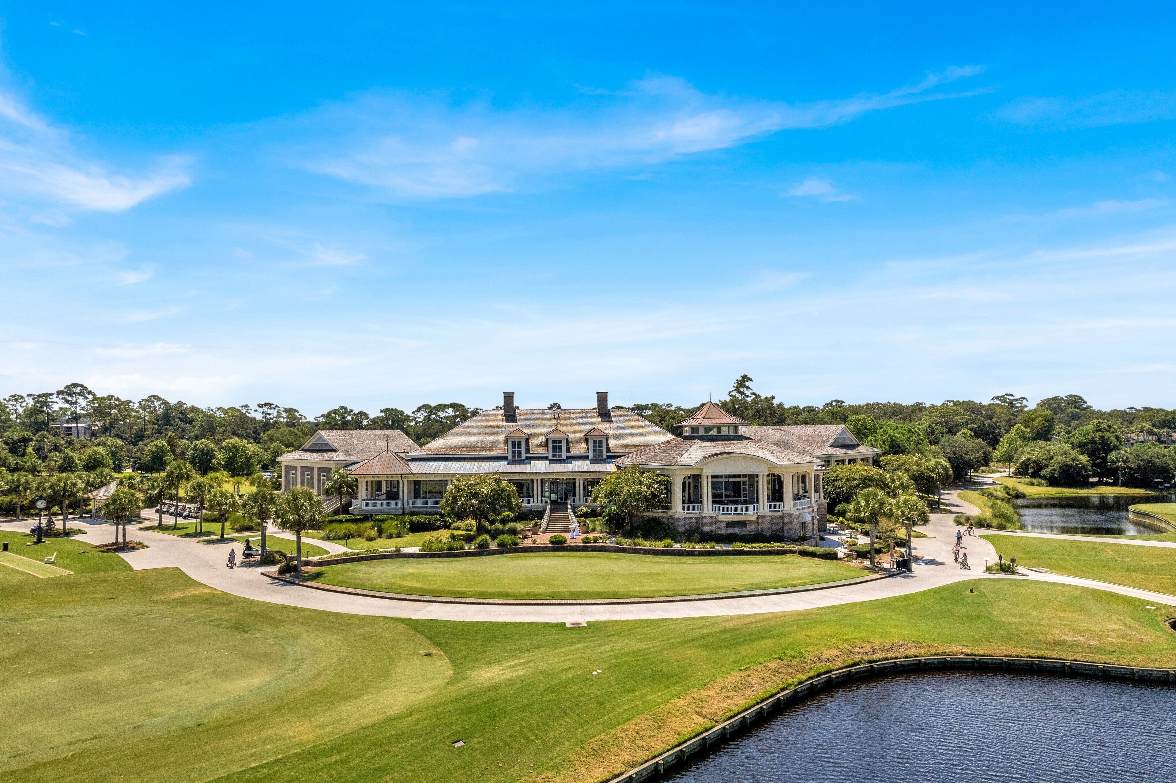 A large, historic mansion with a well-maintained lawn and a pond in the foreground.