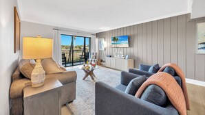 Un salon moderne avec un canapé, des fauteuils, une table basse et un téléviseur.