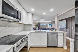 A modern kitchen with white cabinetry, a black stove, a dishwasher, and a microwave.
