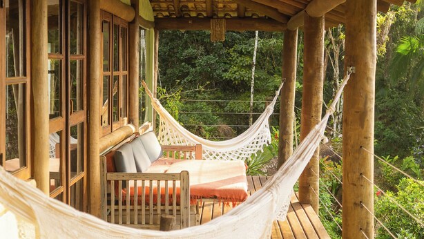 A wooden deck with a hammock and cushioned seating, overlooking lush greenery. - Felix Ocean View, Ubatuba, Sao Paulo, Brazil. (Ubatuba)