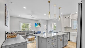Une cuisine moderne avec des meubles gris, un îlot central et des luminaires suspendus.