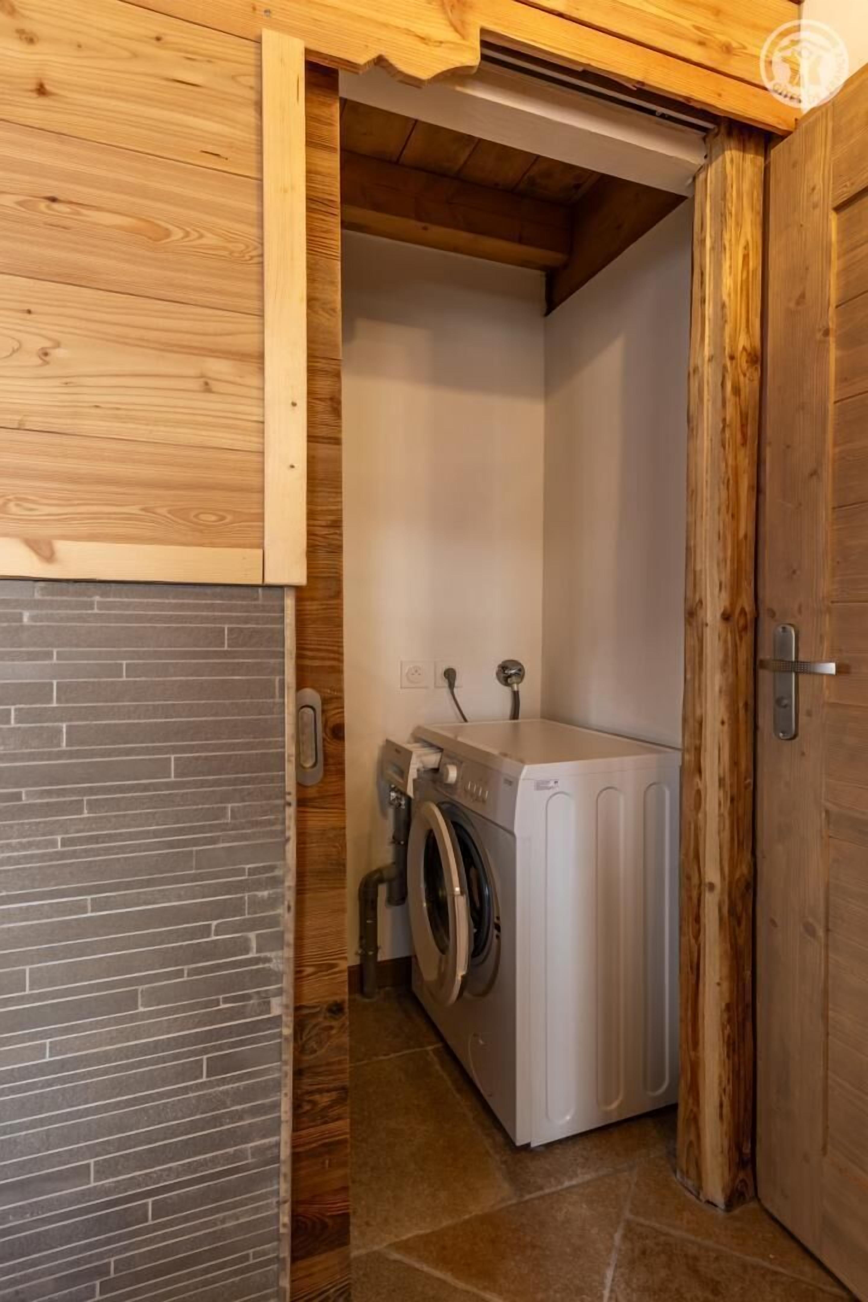 A laundry room with a washing machine and dryer, wooden walls, and a tiled floor.