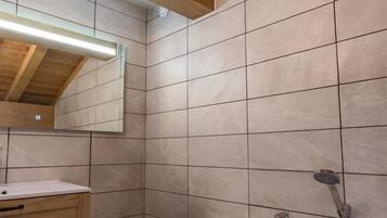 Une salle de bain moderne avec un plafond en bois, une baignoire sur pieds, un meuble-lavabo avec un miroir et des murs carrelés.
