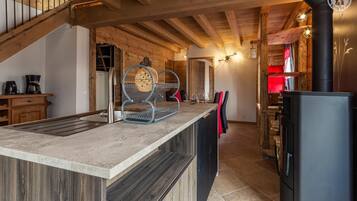 A modern kitchen with a central island, wooden beams, and a black stove.
