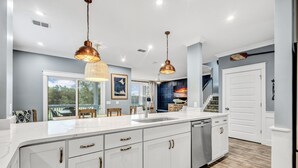Una cocina moderna con armarios blancos, electrodomésticos de acero inoxidable e iluminación colgante.