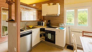 A compact kitchen with a sink, microwave, stove, and cabinets. - Naturastur vacation home (Llanes)