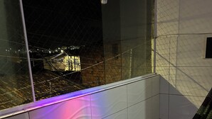 En balkong med utsikt över en stad i natt, med en hängmatta och ett klinkergolv.