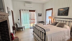 Ein Schlafzimmer mit Bett, Kamin, Sessel, Tisch und einem Gemälde.