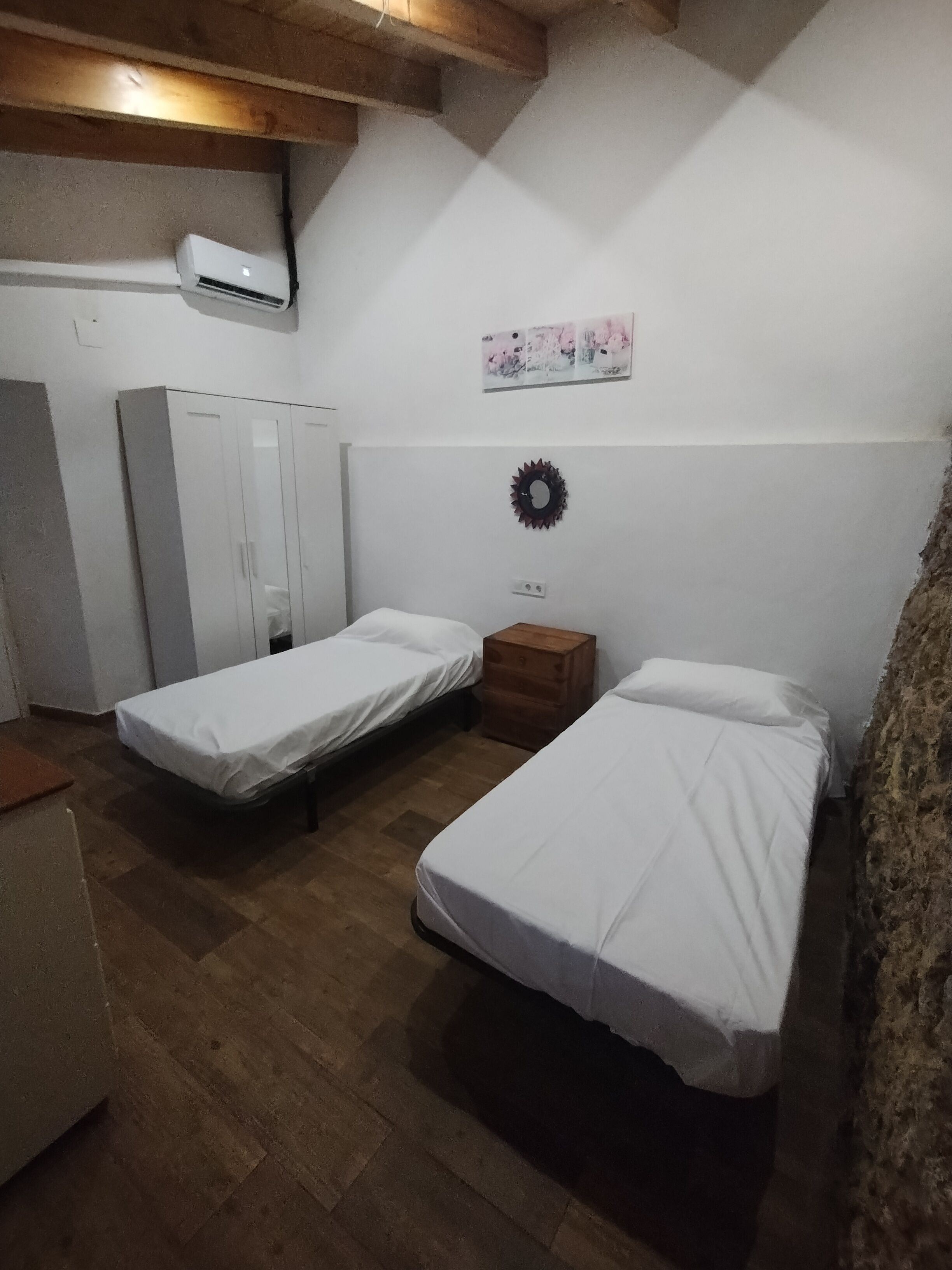 Una habitación pequeña y acogedora con dos camas individuales, un armario y un mueble de madera.