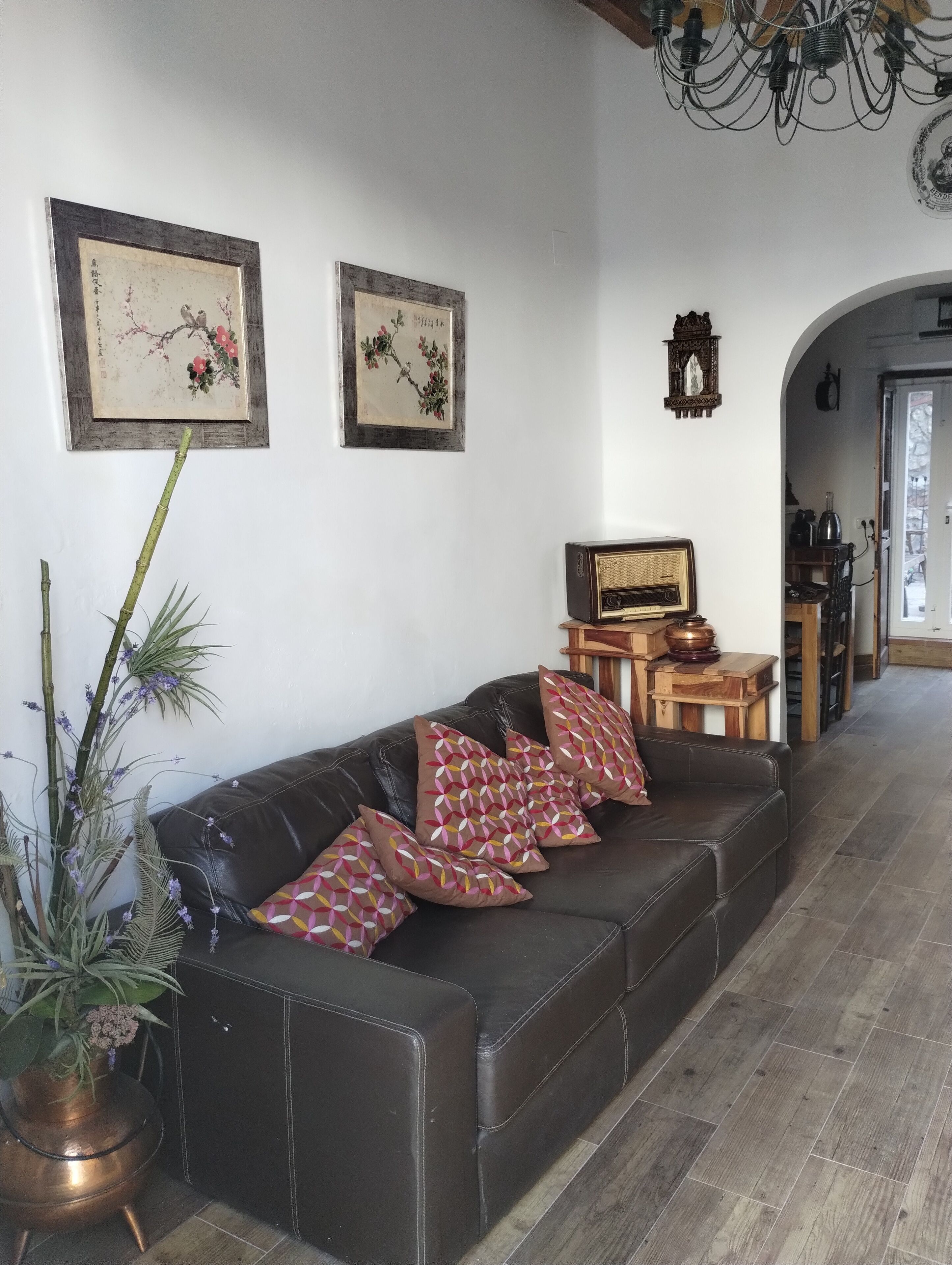 A living room with a leather sofa, decorative pillows, a radio, and framed artwork on the wall.