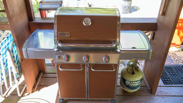 Una parrilla de gas portátil con panel de control y tanque de propano.