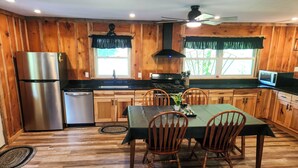 A wooden-paneled kitchen with a dining table and chairs, a refrigerator, a dishwasher, and a microwave.