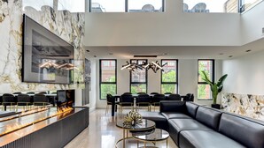 En moderne lobby med en marmorvæg, et ildsted, en sort lædersofa og et spiseområde med stole.