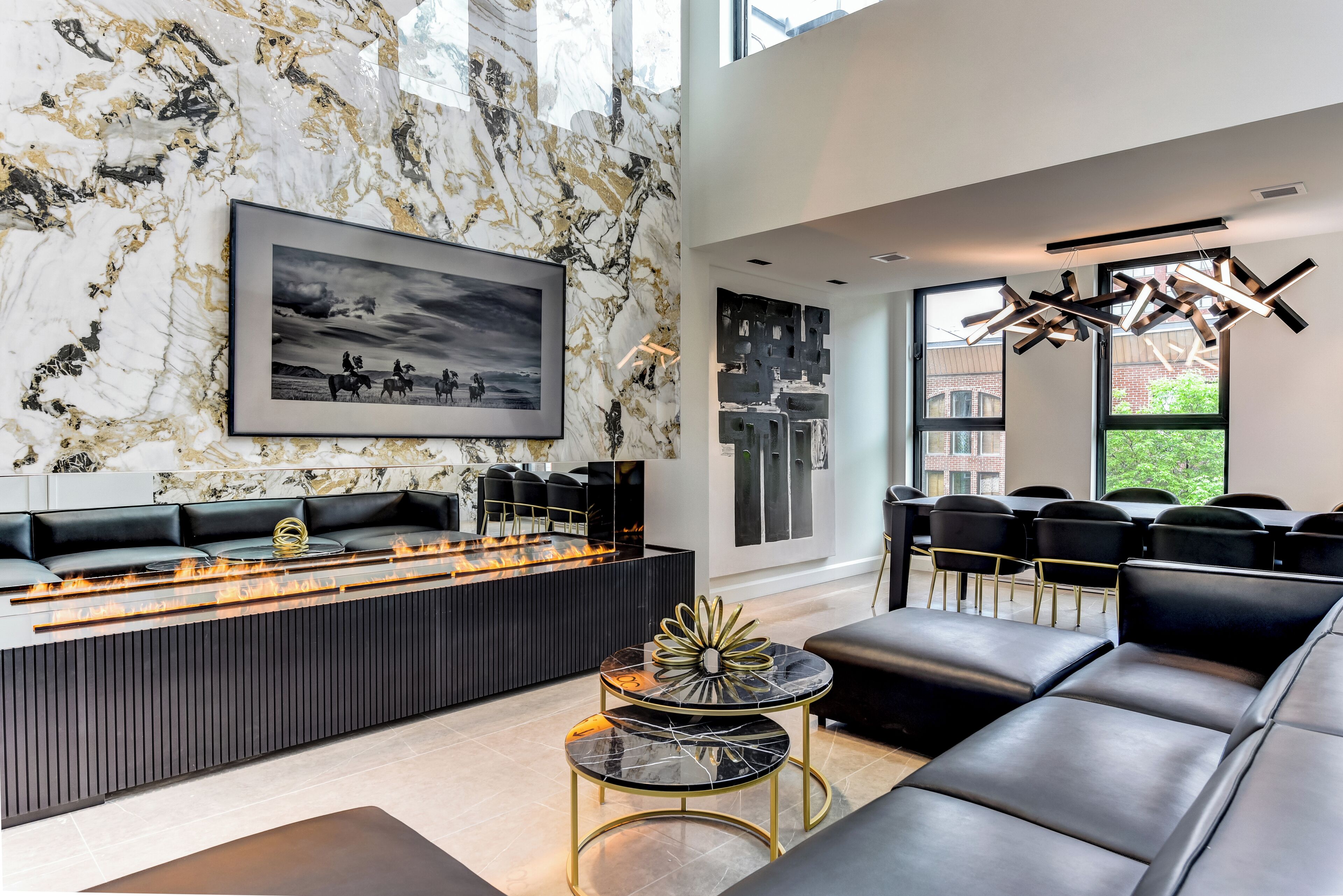 A modern living room with a fireplace, black leather sofas, and a marble wall.