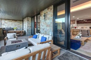 A modern outdoor living area with stone walls, wooden furniture, and a fire pit. - Abode at Empire Residences, ski-in/ski-out, hot tub, empire pass (Park City)