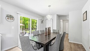 Una sala da pranzo moderna con un tavolo in legno scuro, sedie rivestite di grigio e un lampadario.