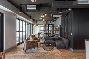 Un intérieur moderne avec une grande fenêtre, un canapé, une table à manger et des luminaires suspendus.