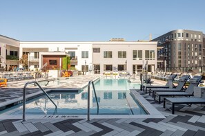 Una piscina en la azotea con sillones de descanso y vistas despejadas de los edificios circundantes.