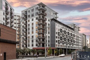 Un immeuble résidentiel à plusieurs étages, doté de balcons, d’une façade en briques et d’une devanture avec une enseigne.